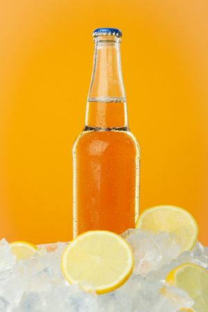 Bottle full of orange liquid on orange background, vertical