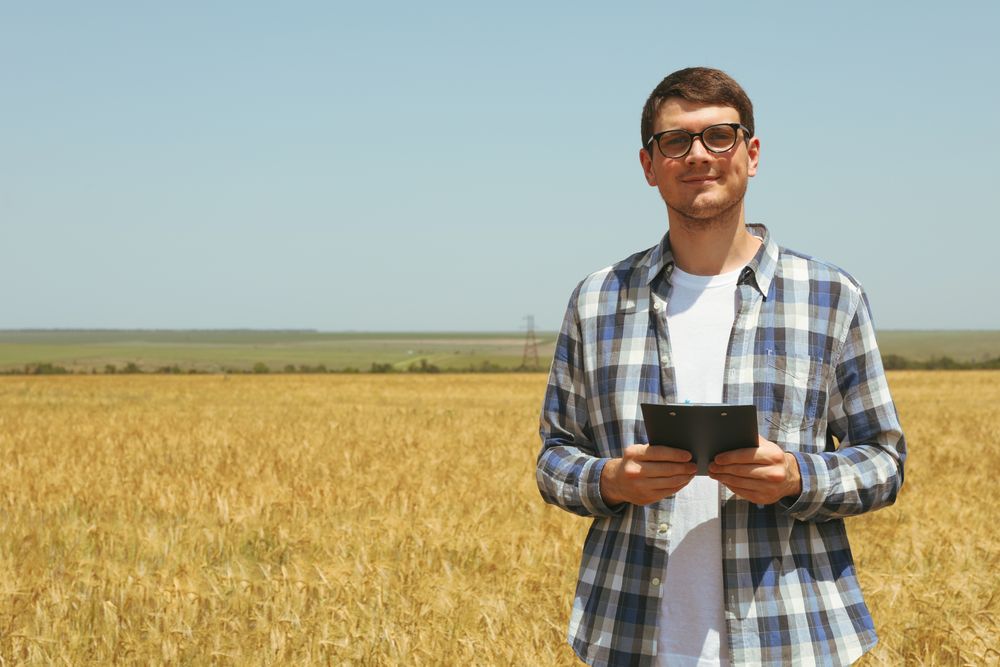Young man with clipboard in barley field. Agriculture business