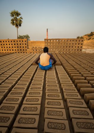 Back view of young man sitting on bricks