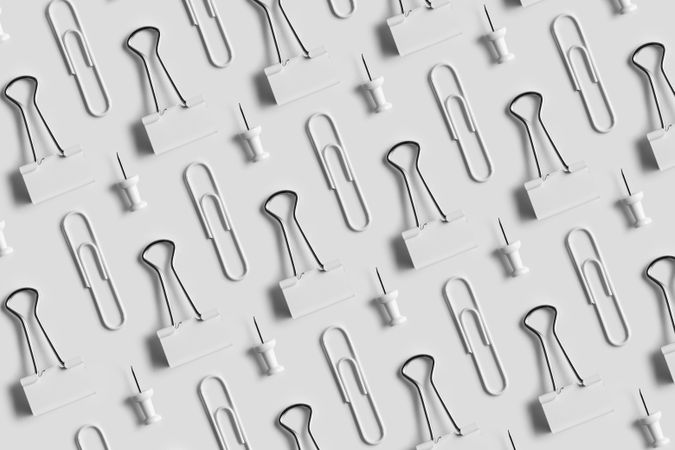 Binder clips, paper clips and tacks on light background