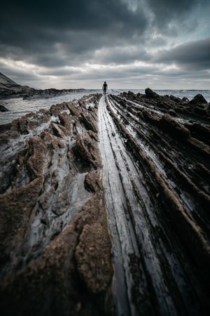 Anonymous person on rough stone shore