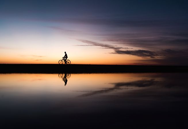 Silhouette of person riding a bike during sunset