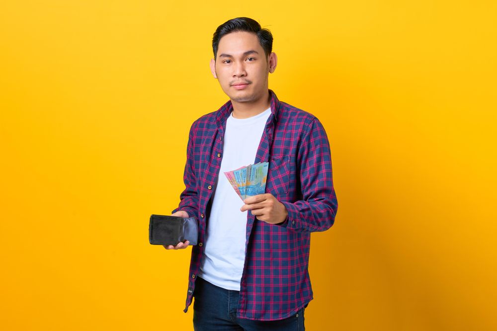Content man holding cash out of his wallet