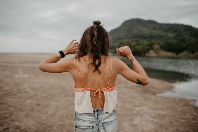 Anonymous female standing towards sea on sunset
