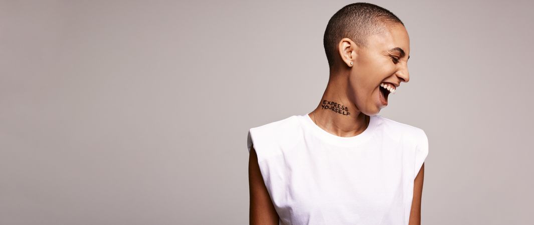 Excited woman with shaved head on colored background