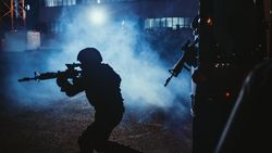 Silhouette of Masked Team of Armed SWAT Police Officers Exit a Black Van Parked Outside of an Office Building.