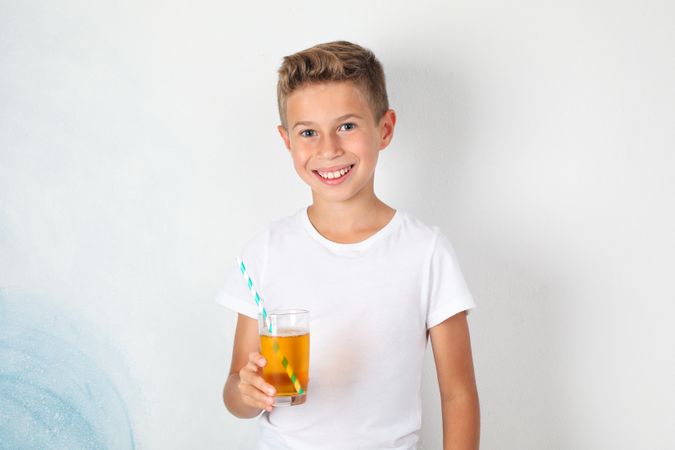 Smile boy with sweet cocktail against blank background