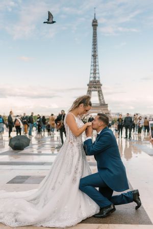 Bridegroom kneeling and kissing hands of bride