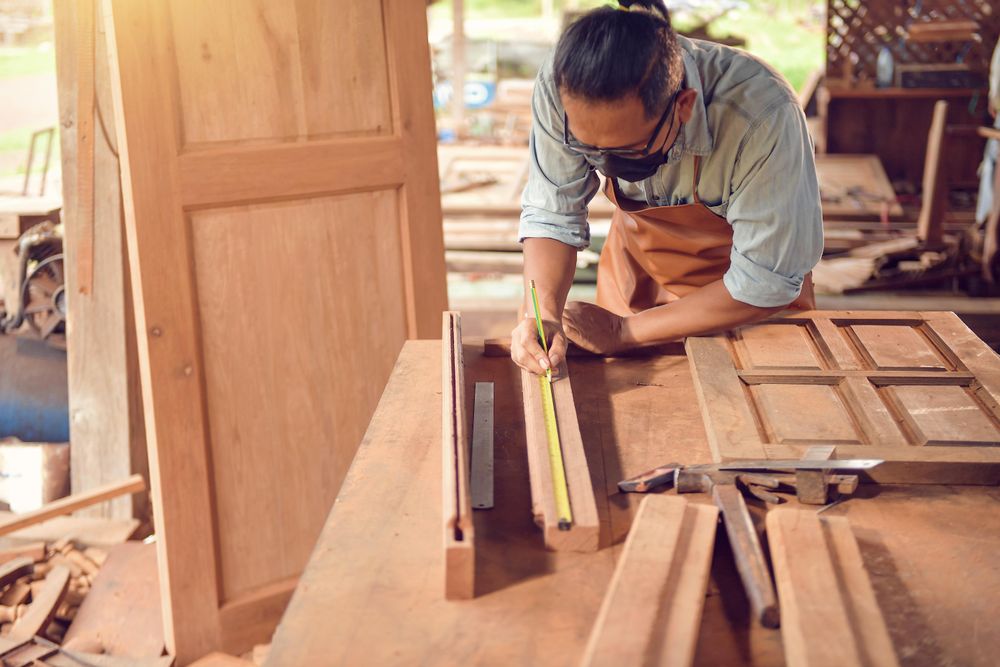 Man with facemask taking measurements of wooden side frame