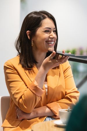 Delighted woman recording audio message on smartphone