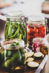 Glass jars of pickled vegetables on kitchen counter, with eggplant slices