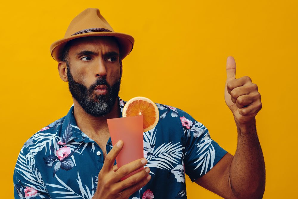 Male giving thumbs up while wearing colorful shirt with yellow background