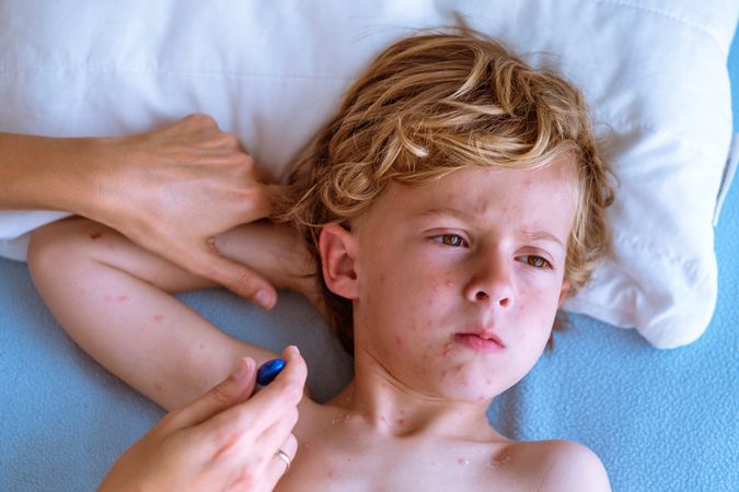Crop mom measuring temperature of sick child