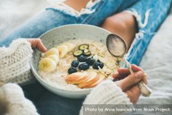 Close up of woman holding bowl of warm oatmeal with fruit, nuts, and honey 5oPgG4