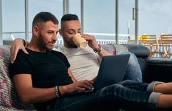Happy gay couple using laptop at home