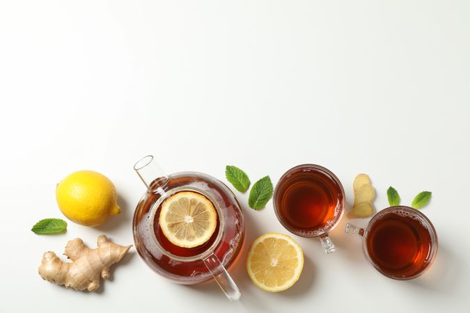 Flat lay. Cups with tea and teapot, lemon, mint and ginger, space for text