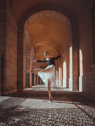 Graceful ballerina in tutu performing arabesque position in arch