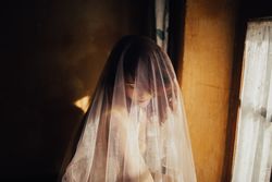 Sensual woman under veil near window