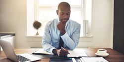 Serious man in suit and tie writing at his desk