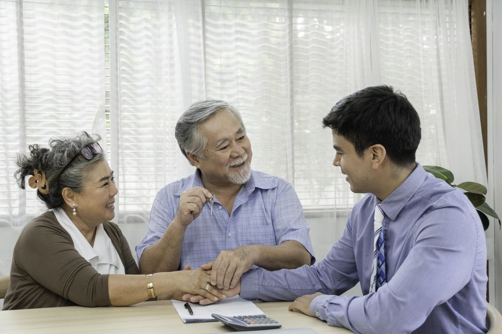 Happy Asian mature couple receiving keys after house purchase