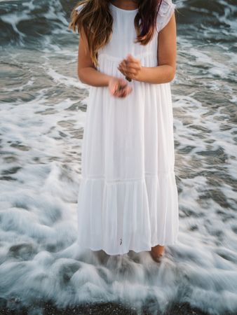 crop girl standing on seaside among waves