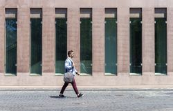 Side view of young trendy professional walking in street wearing smart casual jacket