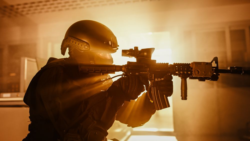 Close Up Portrait of Masked Squad Member of Armed SWAT Police Officers Who Storm a Dark Seized Office Building with Desks and Computers