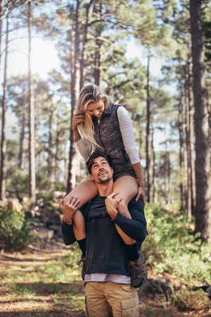 Couple having fun while trekking in forest, vertical