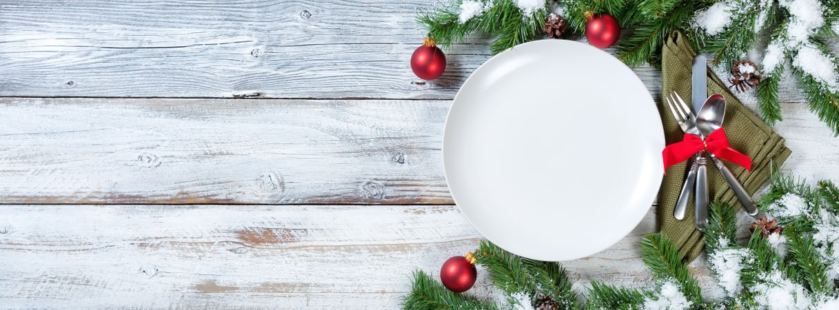 Christmas Table place setting on rustic wood with snow tipped fir branches