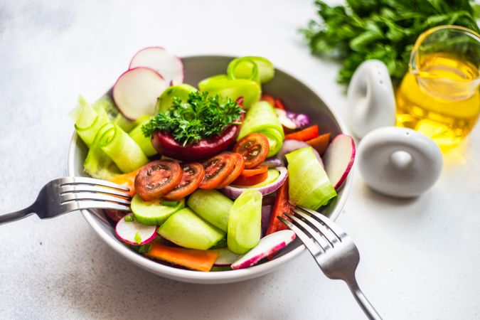 Healthy raw salad with freshly chopped vegetables served with two forks