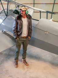 Confident pilot beside retro plane in hangar