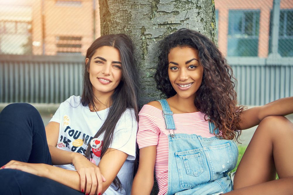 Attractive young females sitting outdoors and smiling at camera