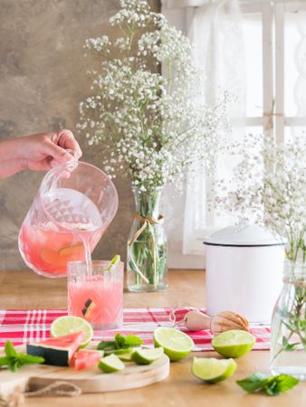 Refreshing watermelon beverage with lime pouring into glass in kitchen