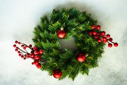 Christmas wreath with red baubles and holly on marble counter