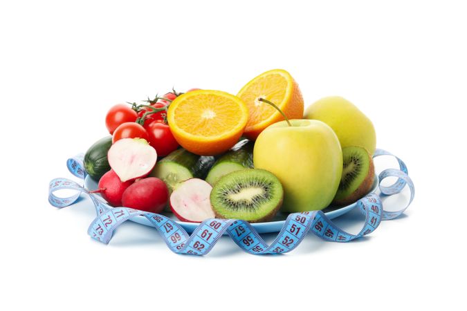 Plate with measuring tape and vegetarian food isolated on blank background
