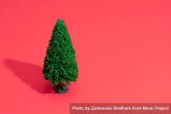 Single green Christmas tree on bright salmon red background 4OO9o4