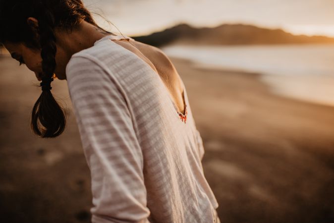 Anonymous female standing towards sea on sunset