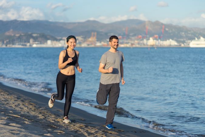 Satisfied sporty couple enjoying in run on seashore