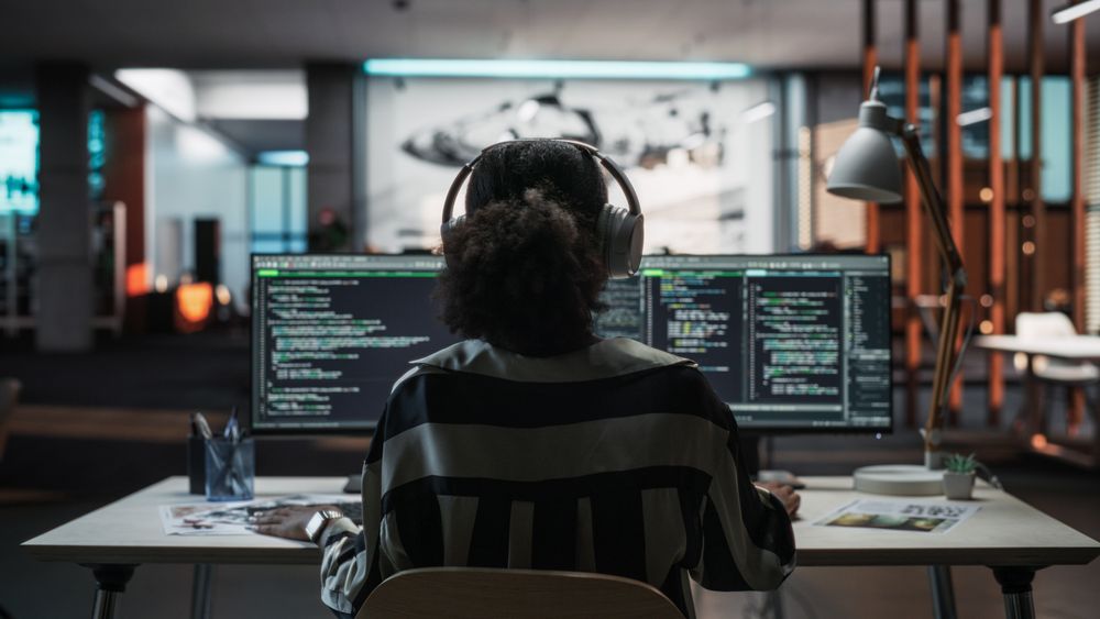 Creative Office: Professional Black Female Programmer Uses Headphones, Working on Desktop Computer.