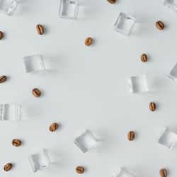 Coffee beans and ice cubes pattern on bright background
