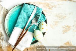 Top view of Easter table setting with ceramic teal plates and spotted Easter eggs 0gXLm8
