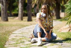 Female sitting on skateboard walkway in park