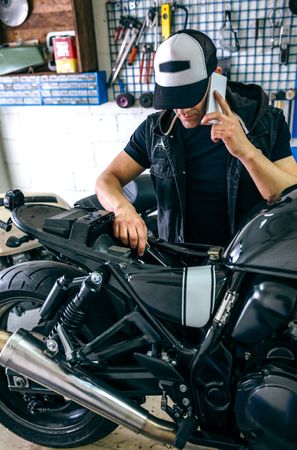 Mechanic talking phone while fixing motorbike