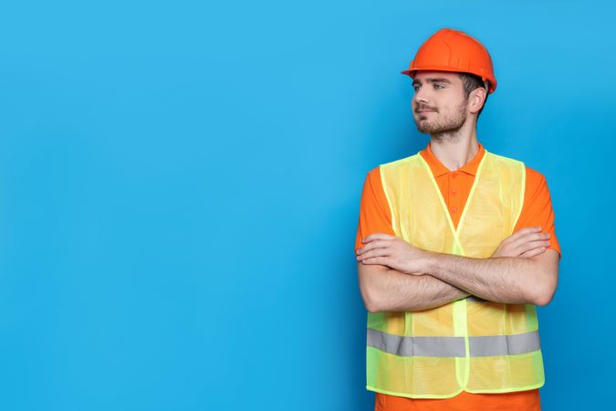 Smiling engineer in helmet on blue background, space for text