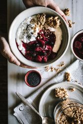 Delicious breakfast bowl with quinoa, rice and groats near tea cup and newspaper
