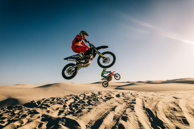 Dirt bikers riding mid air in desert