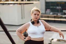Curvy woman with hands on hip on a rooftop during a workout on a roof