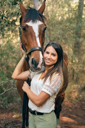 Positive rider embracing horse in forest