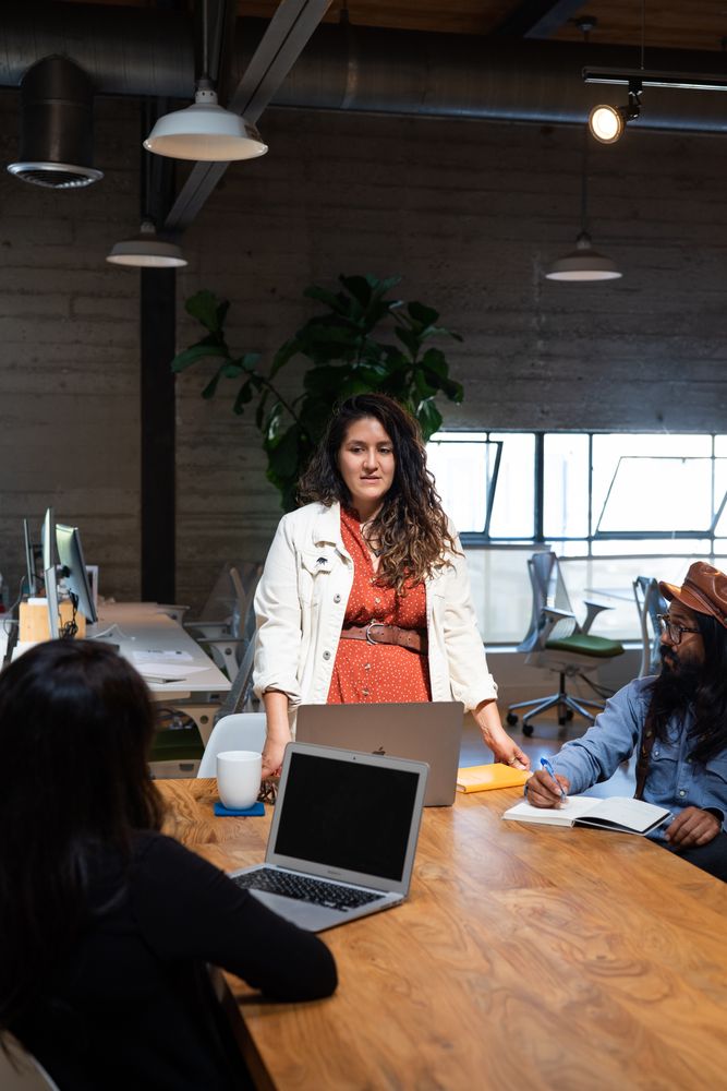Woman standing at table addressing colleagues in an open work space