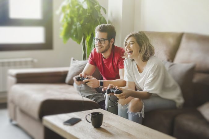 Couple with gamepads playing console